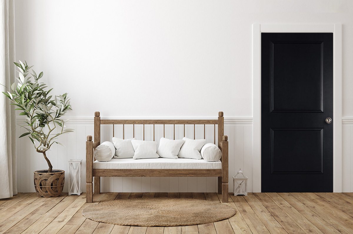 A wooden bench with white pillows in front of a door.